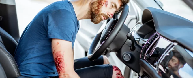 Injured driver sitting behind the wheel after a car accident with visible wounds, illustrating the importance of collecting evidence after a personal injury in West Virginia.