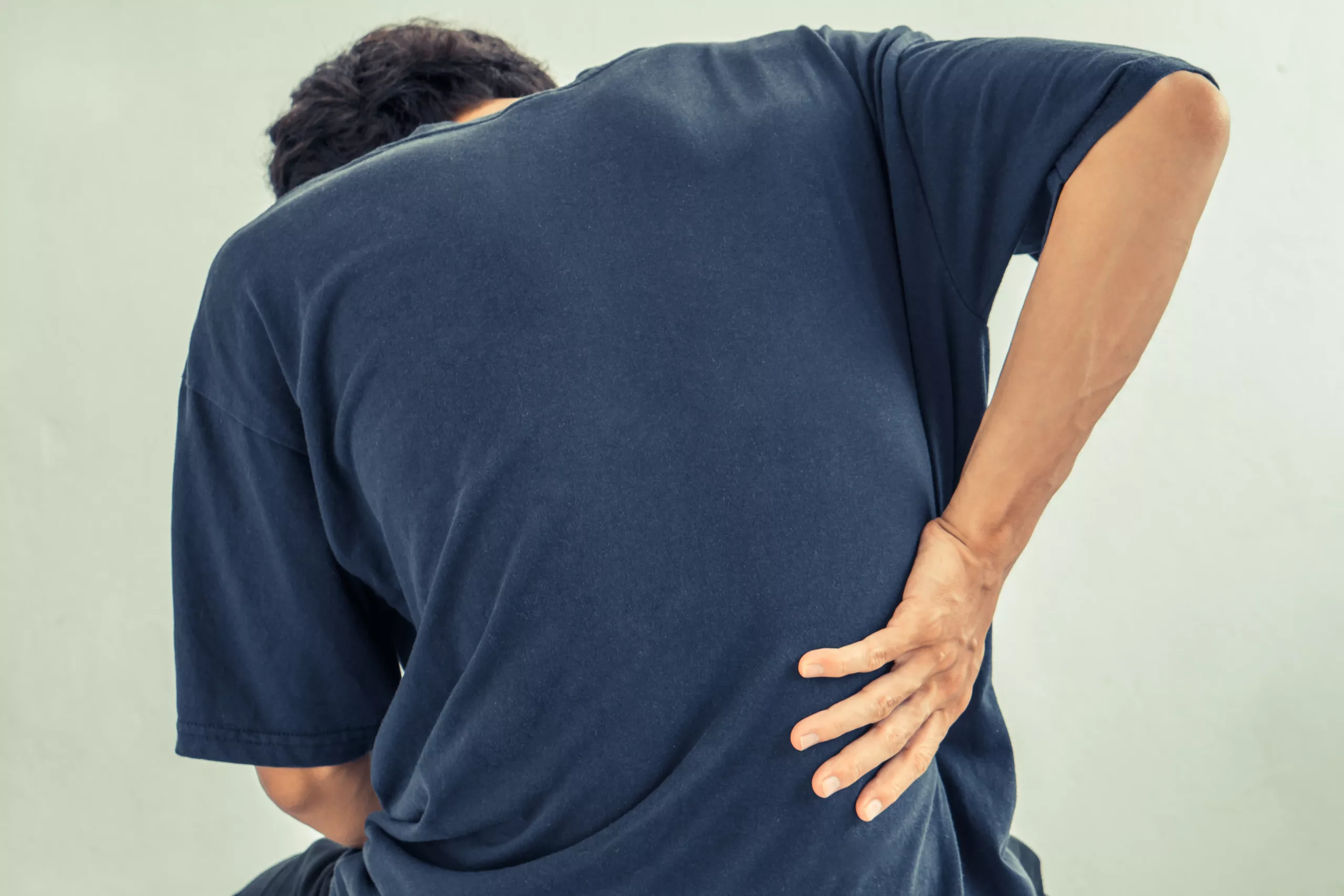 Man holding lower back in pain after car accident in Wheeling