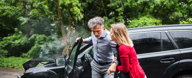 Woman assisting man from damaged car after rideshare accident in Wheeling